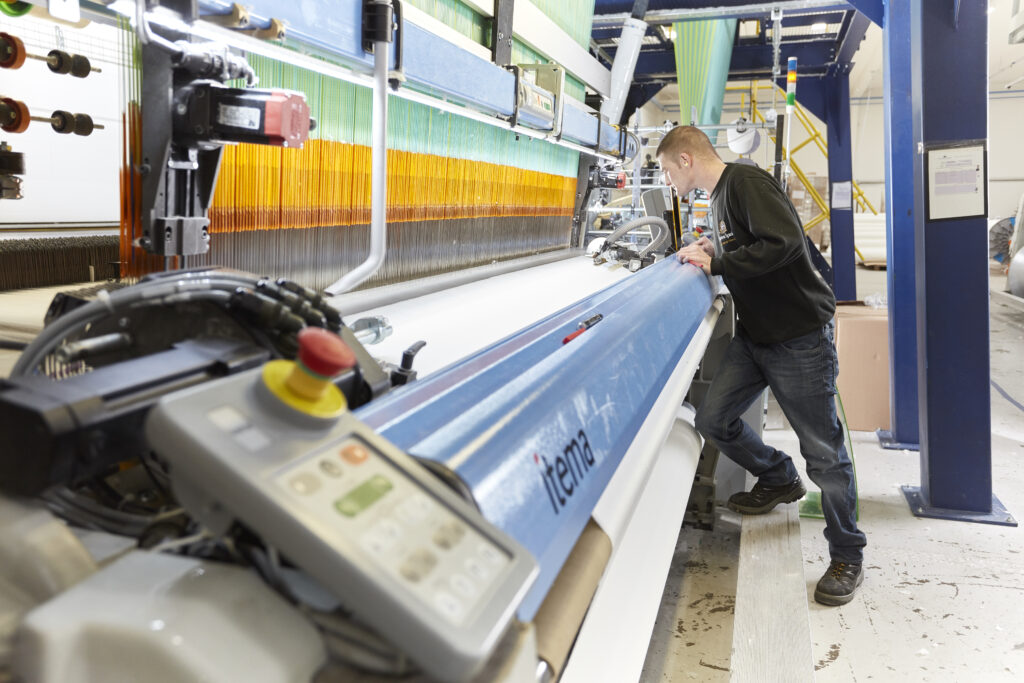 Technicien travaillant sur machine textile Itema pour tissage Harrison Spinks en usine.