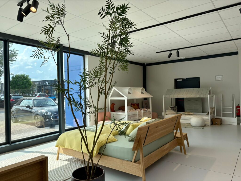Showroom de lit avec maquettes de maisons, plantes vertes et mobilier en bois naturel