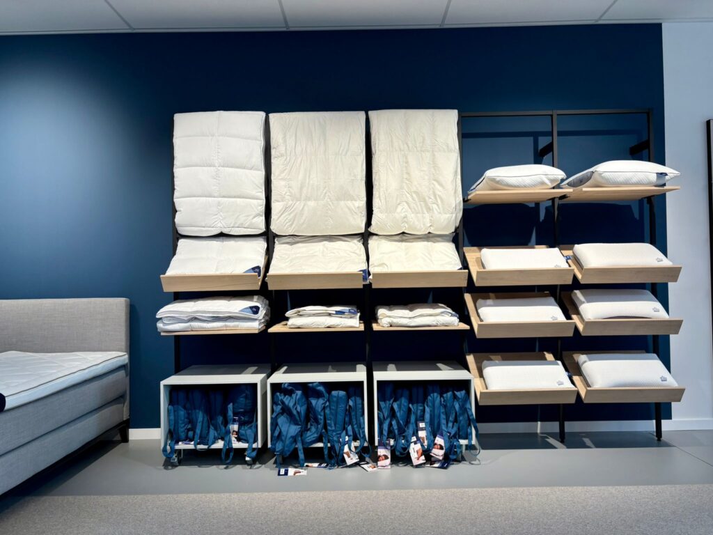 Affichage de matelas et oreillers en showroom avec mur bleu, présentoir de produits de literie