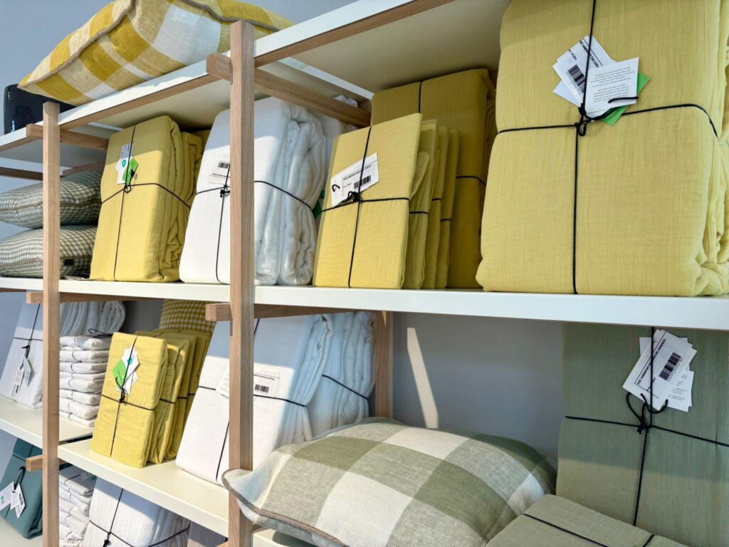 Étagères de magasin présentant des collections de textiles de maison jaunes et gris avec étiquettes