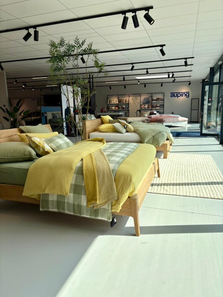 Showroom Auping avec lits en bois, literie jaune et verte, mobilier design scandinave moderne