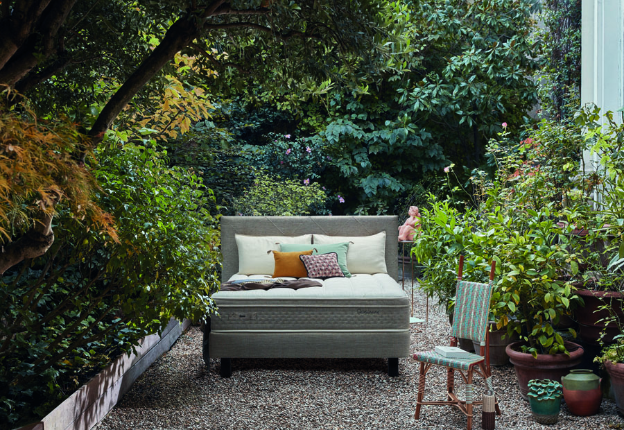 Lit ASTRÉE2 dans jardin luxuriant avec matelas haut de gamme, chaise et plantes vertes